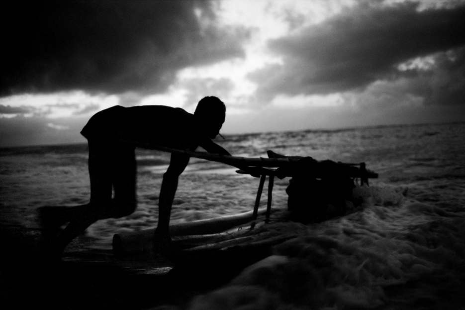 Pescador empurrando o barco ao amanhecer, fotografia de Christian Cravo